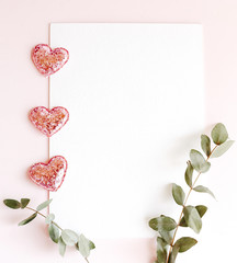 Background with copy space blank on pink background with pink glittered hearts, eucalyptus branch. White paper top view, flat lay, minimal style. Moke up card.