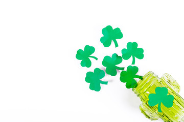 Green paper clover leaves spill out in the form of foam from a green glass