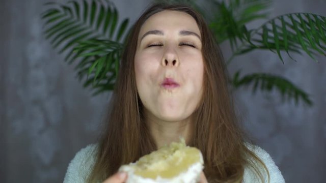 Beautiful girl eating fruit and looking at the camera. The girl eats a pomelo and smiles. A woman looks at the camera and eats a citrus. Woman enjoying the food.Vegetarianism.Healthy food. Healthy foo