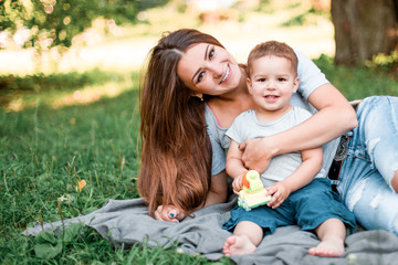 Mother with little son spend time together in green park.