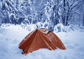 Camping tent on snow in snowy winter forest after snowfall