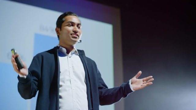 Portrait of Successful Inspirational Speaker, Talking about Happiness, Self, Success, Empowerment, Efficiency and How to Be More Productive Self. Large Conference Hall with Cinematographic Light