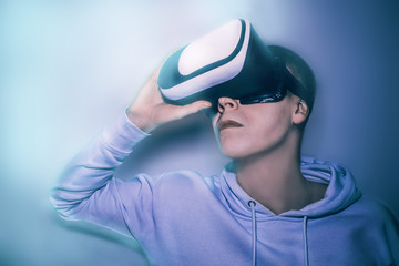 Young man looks into virtual reality glasses in neon blue light close-up