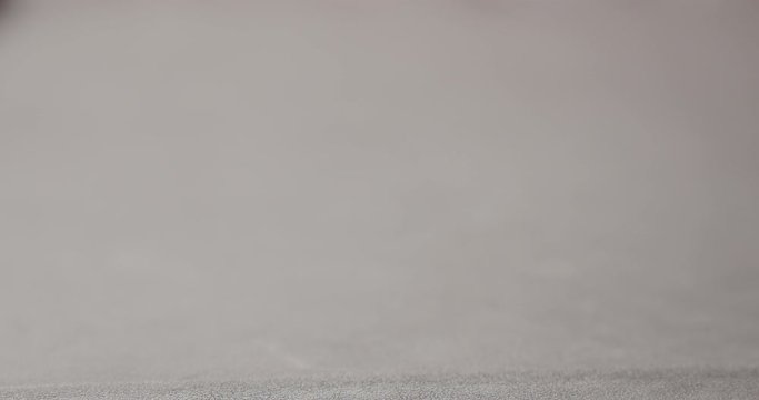 Slow motion unroll brown leather piece on walnut table closeup