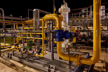 Pipeline system at a gas production and processing plant. Pipes, valves, manometers. Night shooting