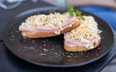 Two sandwiches on a black plate outdoors.