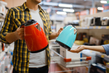 Couple choosing electric kettle, electronics store