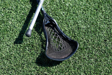 Various styles and colors of Lacrosse sticks on artificial turf during a womans Lacrosse tournament