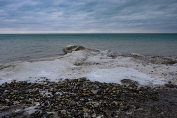 Fototapeta na wymiar Ice floe buildup along the rocky shoreline of Lake Michigan on the United States side on a cloudy cold winter day
