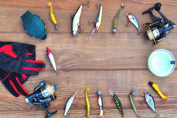 fishing accessories fishing rod, reel with fishing line, silicone baits and lures, spinning gloves and accessory box on a wooden background,  copy space flat lay