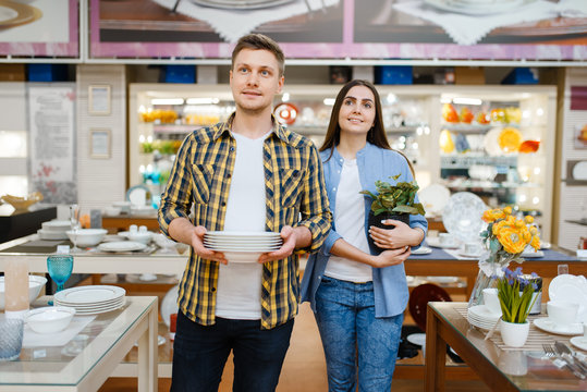 Young couple with plates in houseware store