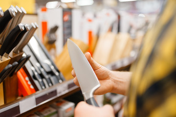 Young man choosing kitchen knife, houseware store