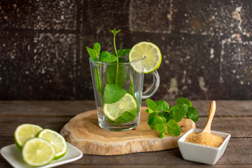 Empty glass teacup with fresh mint leaves and slices of lime on a wooden board.