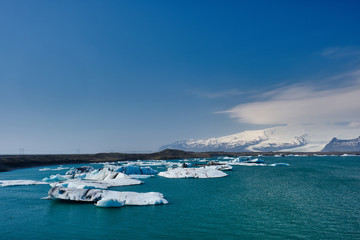 Icebergs and ice flowes calved off the glacier slowly flow out to the ocean from the lagoon