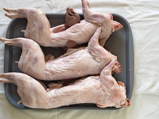 Carcass of raw rabbit meat on a glass baking sheet. Home cooking, cook at home.