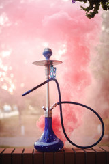 Hookah outdoors on a background of colored smoke