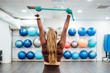 Beautiful woman in gym performing exercises with elastic bands.