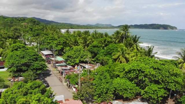 Aerial shot over the village of Samara, shot towards the beach and the sea, including palm trees and sunny weather. Samara, Costa Rica.