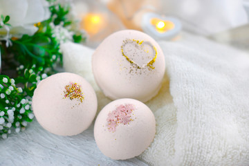 Romantic spa cosmetic composition. Close up bath bombs, flowers, candles, towel on white background. Love or health lifestyle concept