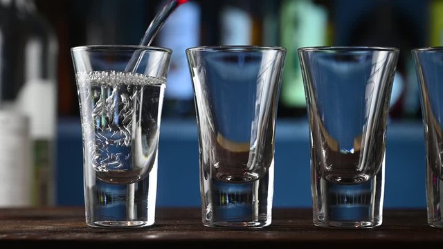 alcohol pours into a glasses in a bar background