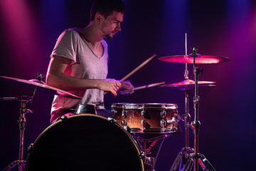 The drummer plays the drums. Beautiful blue and red background, with rays of light. Beautiful...