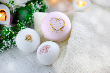 Close up bath bombs with roses, heart, towel on light background. Romantic spa lifestyle concept for Valentines day, Mothers day or wedding greeting card.
