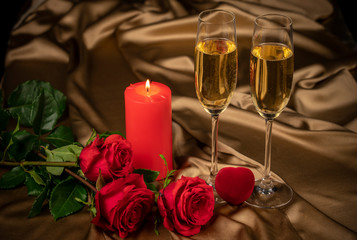 Valentine's day card, two glasses of champagne on a gold background red roses and a red heart, a lighted candle