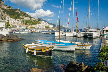 Fototapeta na wymiar Traditional boats and modern yachts docked at Amalfi marina, Italy.