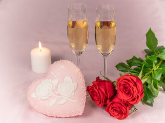 Valentine's day card, two glasses of champagne on a pink background red roses and a pink heart, a lit candle