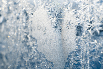 Fototapeta na wymiar The inscription: goodbye, winter. On a frozen winter window in frosty patterns