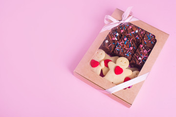 A set of sweets in a box with satin ribbon on the pink background. Shortbread cookies with heart, chocolate brownie.