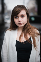 Girl in winter in a cardigan on a street in the city