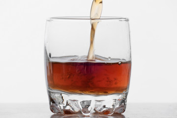 Glass of whiskey with ice isolated on white background  Process of filling glass by whiskey on white background
