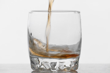 Process of filling glass by whiskey on white background