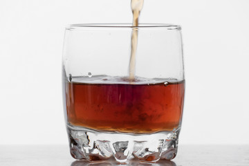 Process of filling glass by whiskey on white background