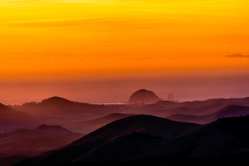Fototapeta na wymiar Orange Glow of Sunset over Ocean and Mountains