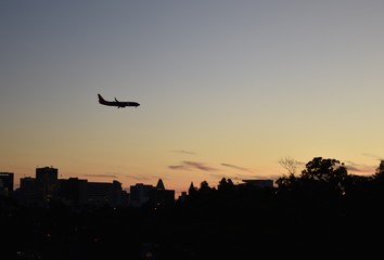 A plane comes in for a landing at dusk, with the San Diego skyline in the background.