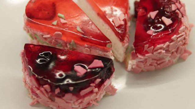 two round cakes with berry filling and two heart-shaped cakes cut in half on a white plate close-up