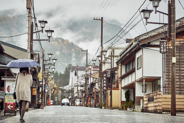 Girl Walking down Street of Traditional Japanese Mountain Town in fog and rain 