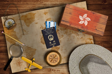 Top view of traveling gadgets, vintage map, magnify glass, hat and airplane model on the wood table background. On center, official passport of Hong Kong and your flag.