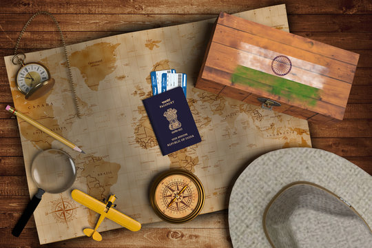 Top view of traveling gadgets, vintage map, magnify glass, hat and airplane model on the wood table background. On center, official passport of India and your flag.