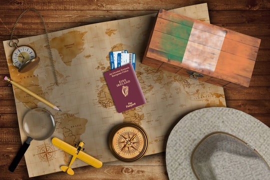 Top view of traveling gadgets, vintage map, magnify glass, hat and airplane model on the wood table background. On center, official passport of Ireland and your flag.