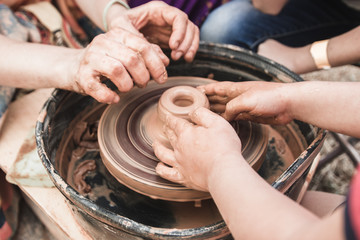 A close up view on ceramic production process on potter's wheel with children. Clay crafts with kids concept.