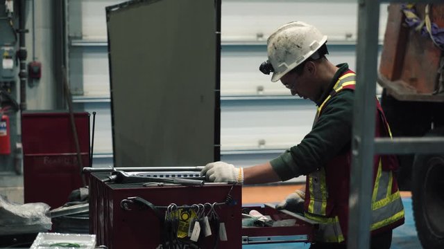 The mechanic takes the documents out of the nightstand. He fills out a sheet. It's a mandatory procedure. He's wearing glasses, a reflective vest and a helmet. It's for safety.