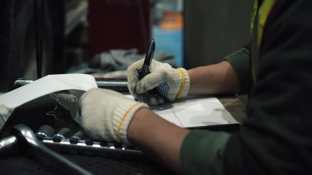The mechanic takes the documents out of the nightstand. He fills out a sheet. It's a mandatory procedure. He's wearing glasses, a reflective vest and a helmet. It's for safety.