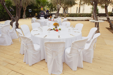 Beautiful white table and chairs in restaurant. Wedding party setting with white draperies