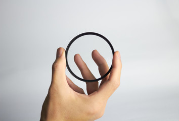Hand holds clear lens camera filter on white background