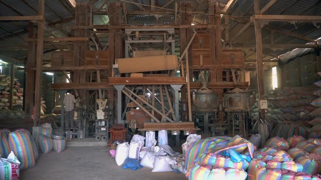 Rice milling system during the different processing steps for produce an edible rice. Rice bags inside workshop ready for transport.