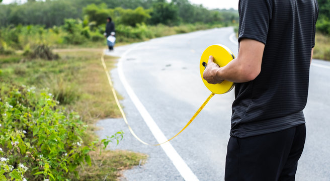 Close up of man hand measuring a long distance using rolling distance measuring tape.