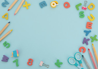 Soft English letters and numbers with school and office supplies on blue background. Back to school, stationary concept. Kid's set for teaching reading and counting. Flat lay style with copy space.